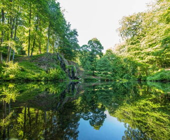 Landschaftsaufnahme mit Luisenthaler Wasserfall und Teich im Schlosspark Altenstein